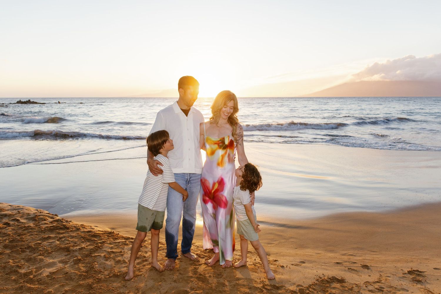 A group holds hands while walking along a scenic beach at sunset.