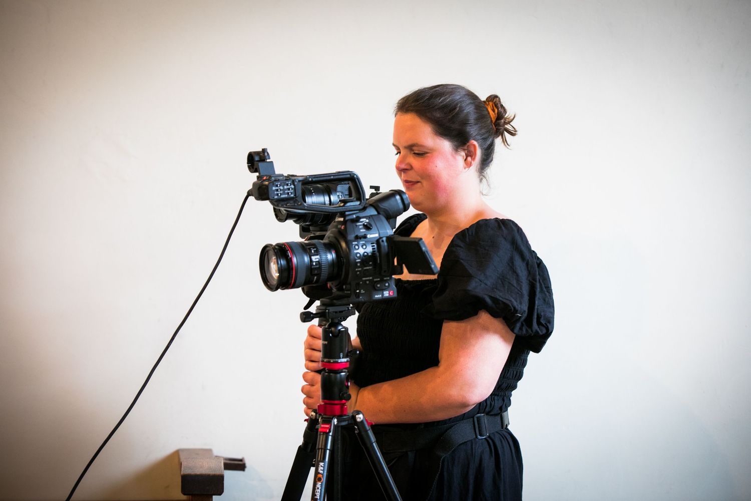 A photographer works with camera equipment near wooden stables.