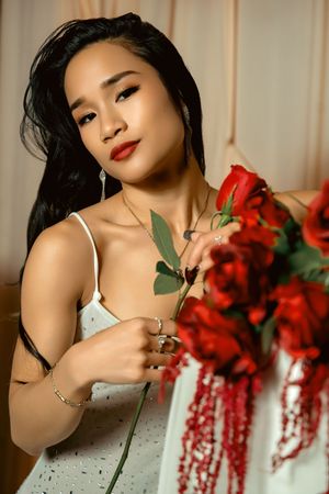 A series of artistic boudoir portraits with red floral arrangements against a white backdrop.