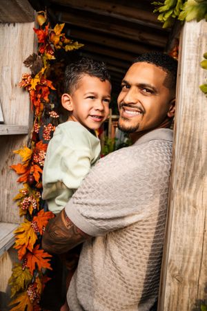 Father and young son share tender moment among fall decorations.