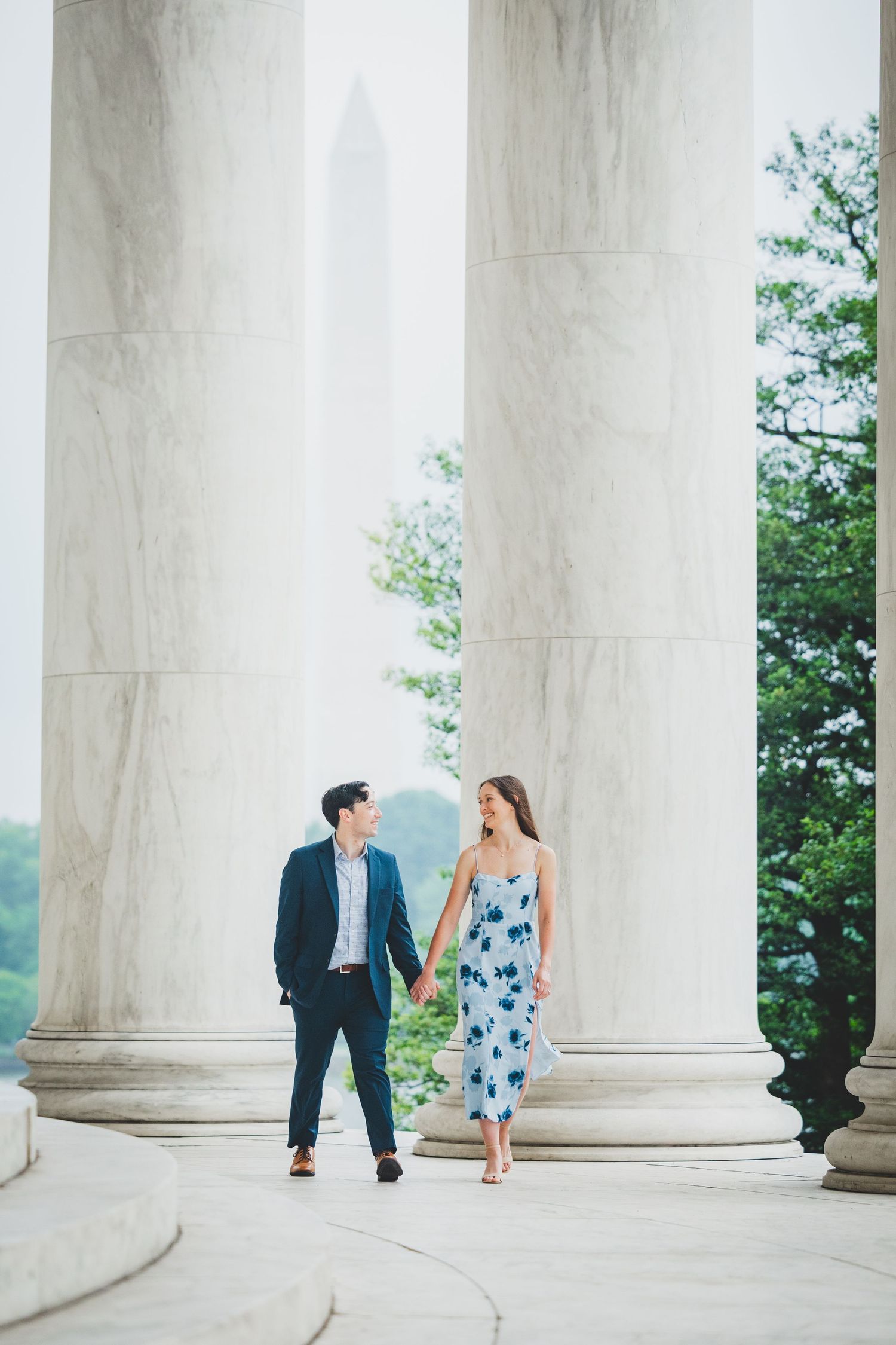 A couple shares a romantic moment between white marble columns at the Jefferson Memorial in Washington DC.