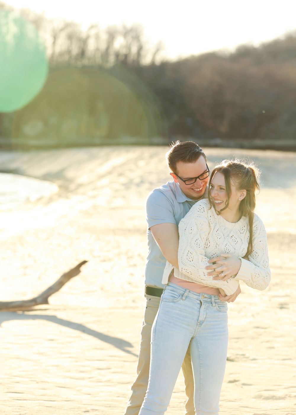 Couple embracing and laughing together on a sunny beach.