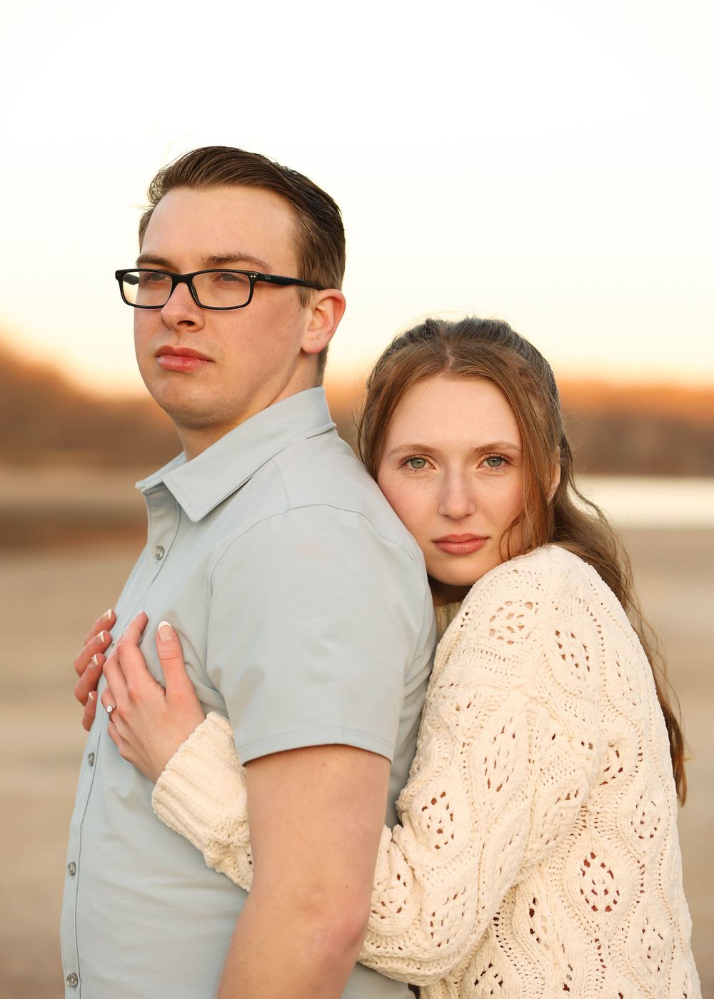 A couple poses together during sunset wearing coordinated casual outfits.