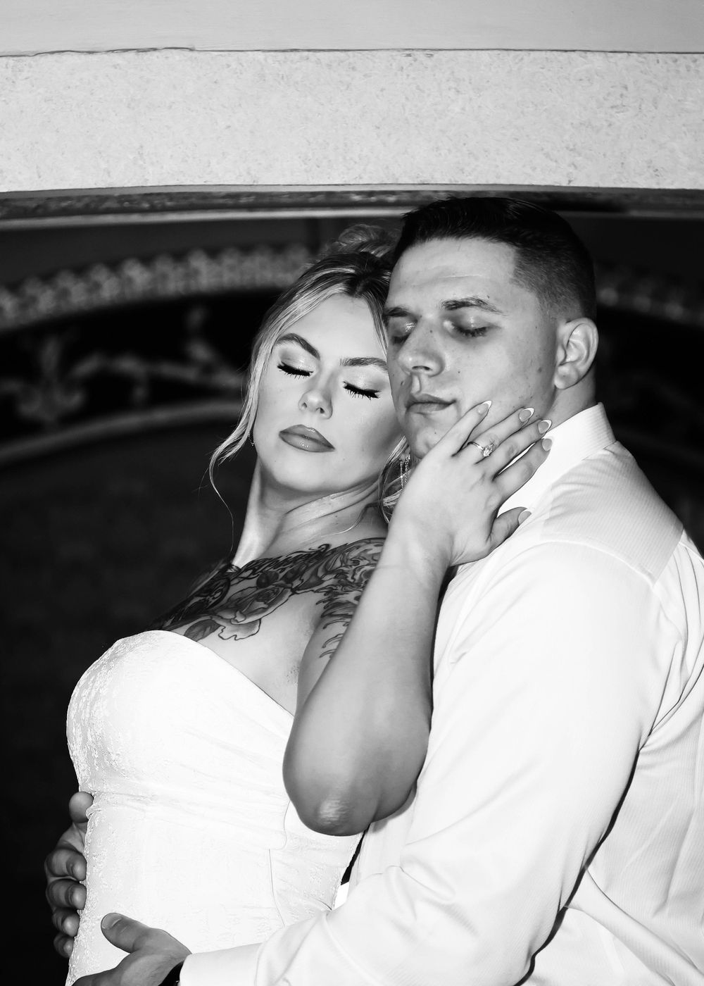 An intimate black and white portrait of a couple in white clothing.