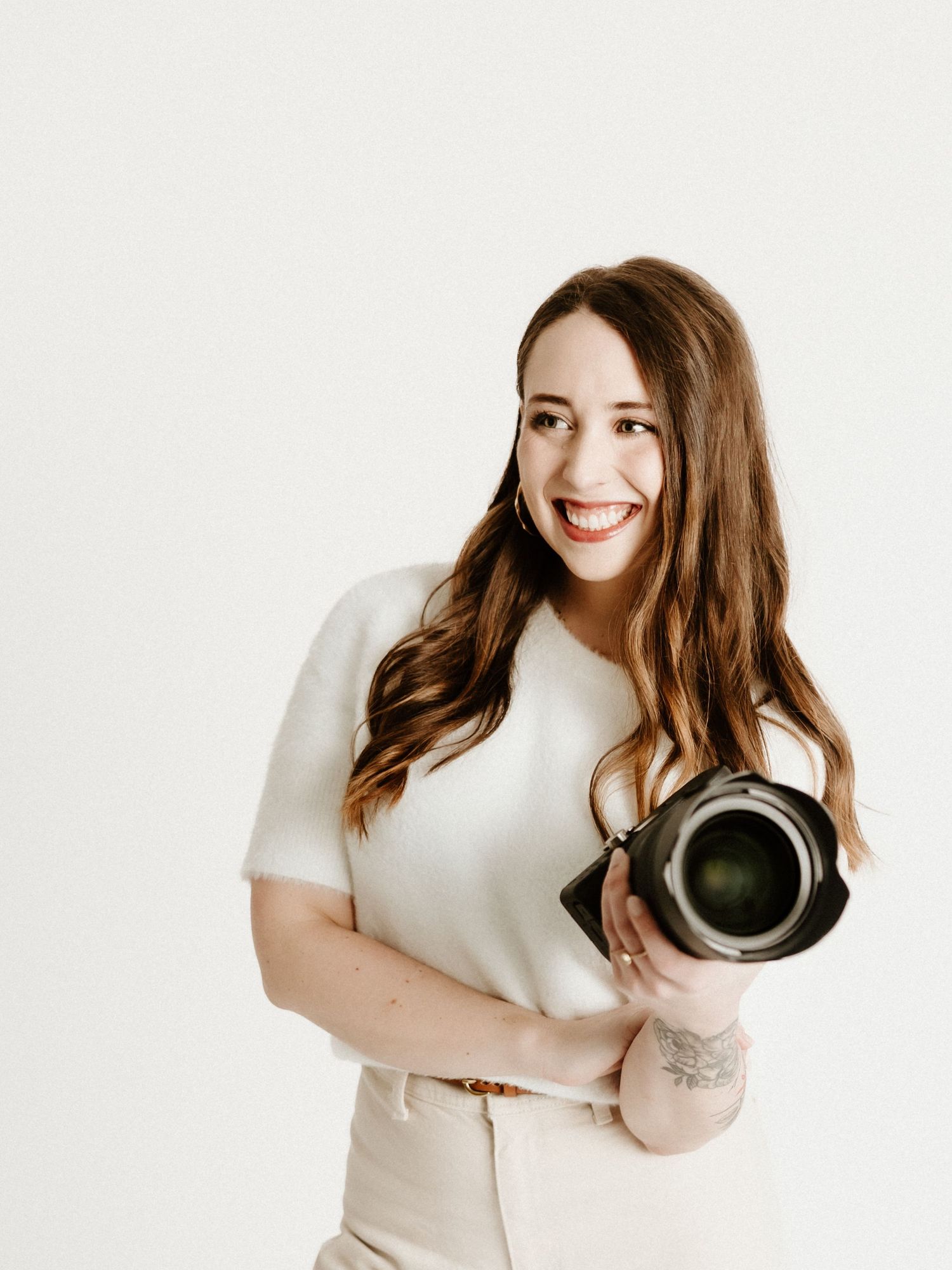 A person dressed in white and cream lounges comfortably on a minimal white studio background.