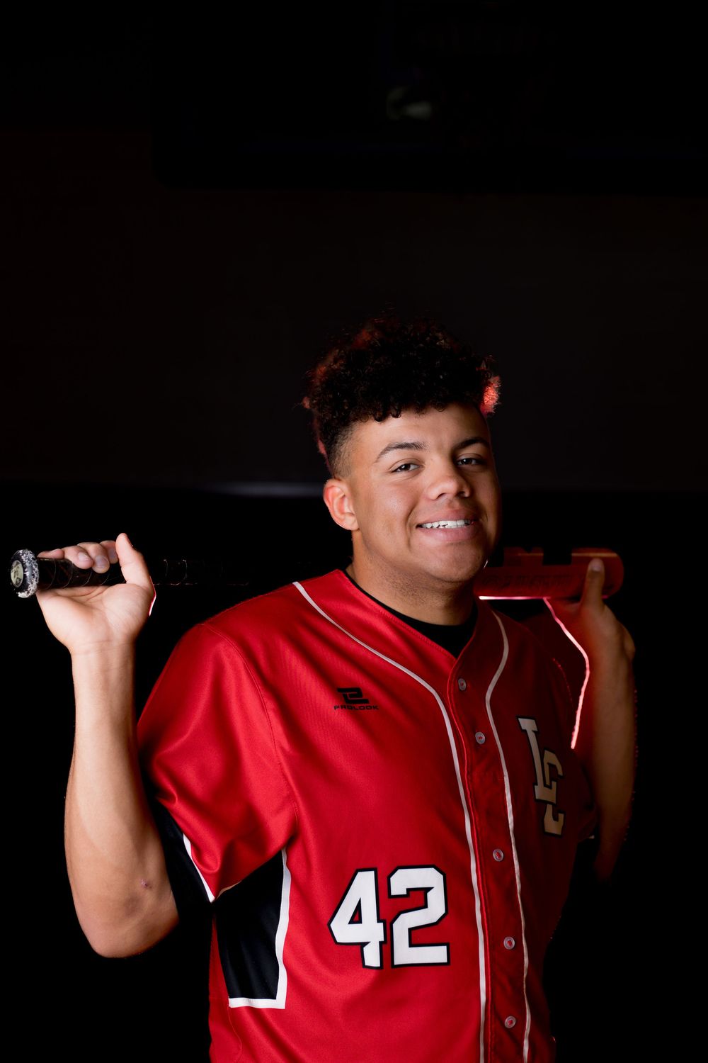 Baseball player in red jersey number 42 poses with bat against dark background in four sequential shots.
