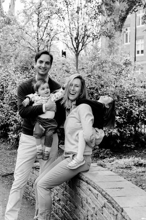 Family session in a park in Zurich. Mum is laughing while the kids are pulling at her. Black and white family image. Zurich photographer