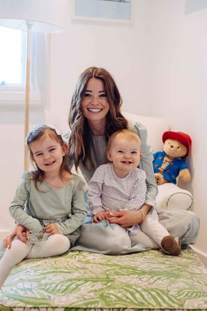 London family photographer, Mum is sitting with her two daughters. Mum is wearing a beautiful mint dress.