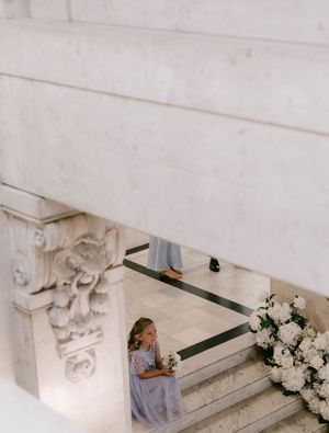 Elegant white floral arrangements adorn marble steps in a classic architectural setting with ornate details.