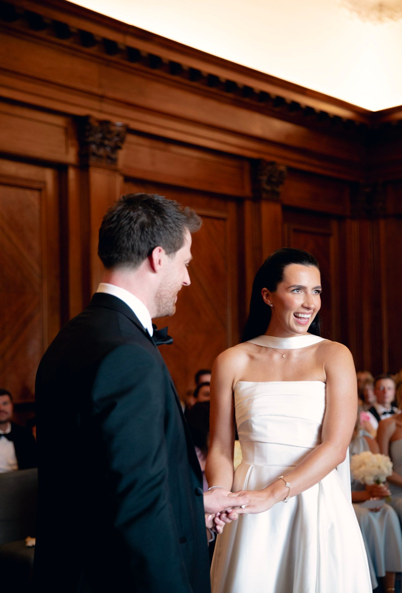 Candid moments of a wedding ceremony in Old Marylebone town hall in an elegant wood-paneled room.