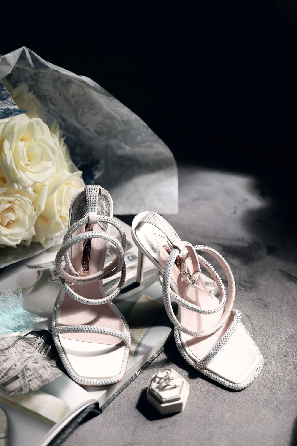 Elegant bridal shoes with crystal details displayed with white roses The Franklin Boutique Hotel Starthotels Collezione