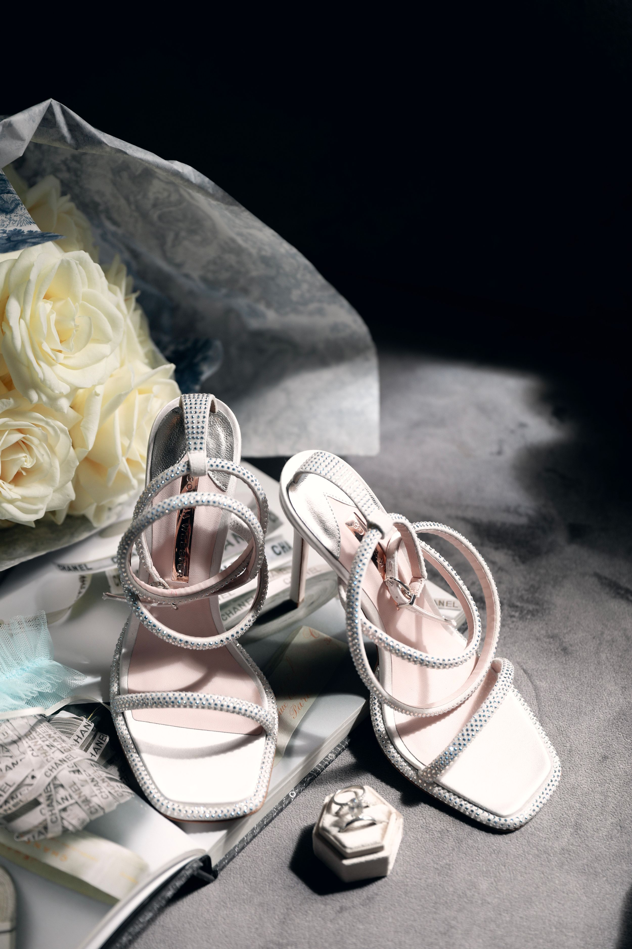 Elegant bridal shoes with crystal details displayed with white roses The Franklin Boutique Hotel Starthotels Collezione