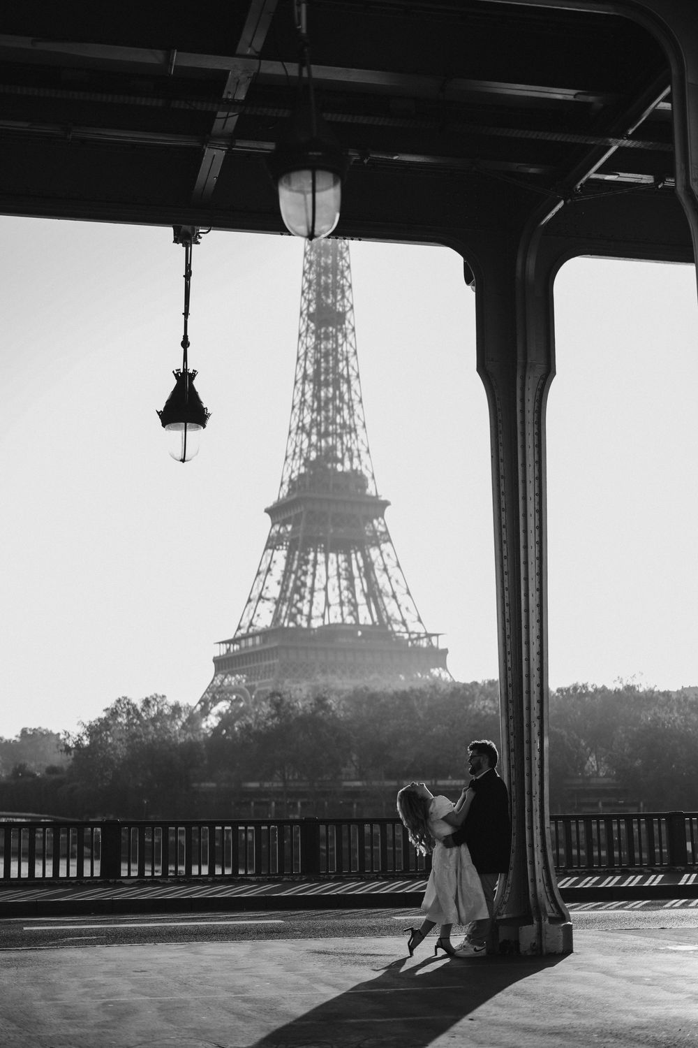 Black and white photo of a couple dancing on Bir-Hakeim Bridge with the Eiffel Tower in Paris background.
