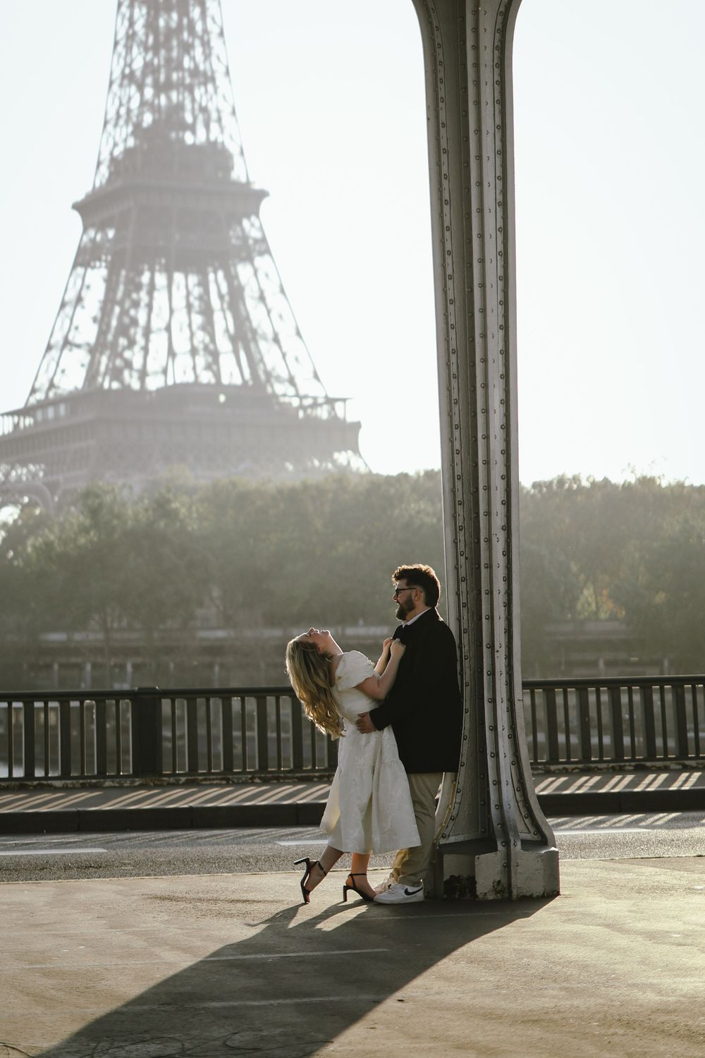 Romantic couple embracing near Eiffel Tower in Paris, France on a sunny day.