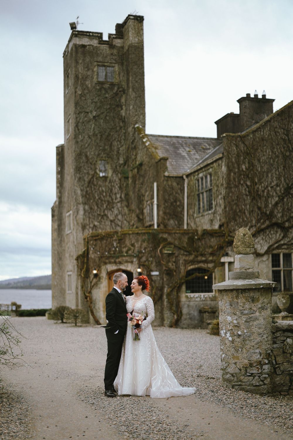 Bride and groom share a romantic moment outside a historic Irish castle venue on their wedding day.