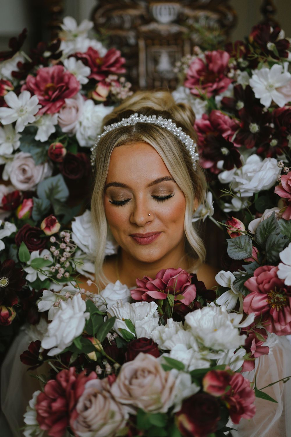 A romantic bridal portrait series surrounded by pink and white floral arrangements and delicate greenery.