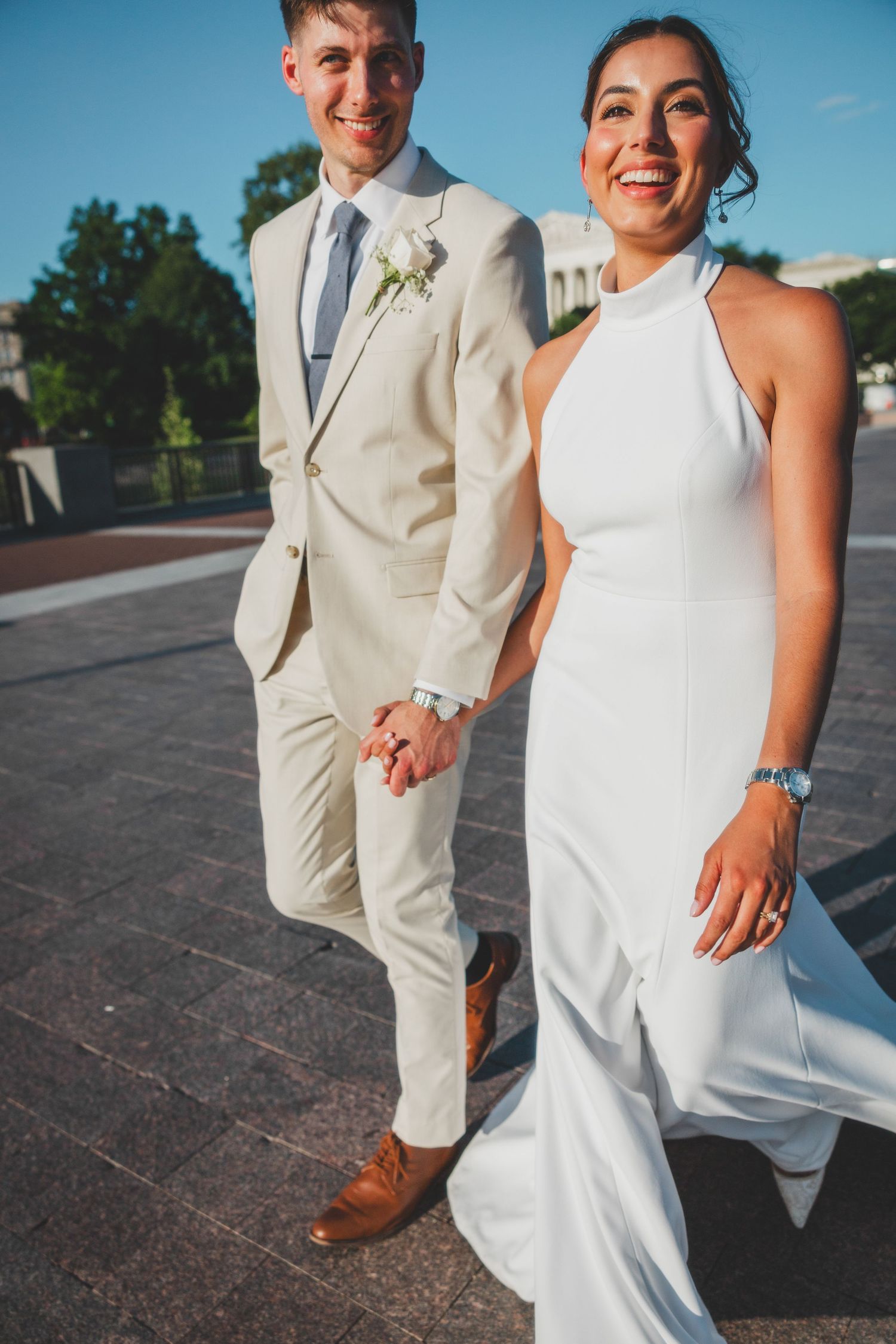 Happy couple in matching white and beige attire walking outdoors.