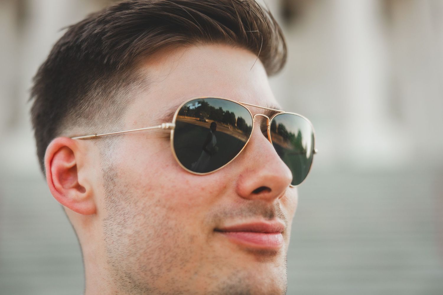 Close-up of person wearing aviator sunglasses with Capitol dome in background.