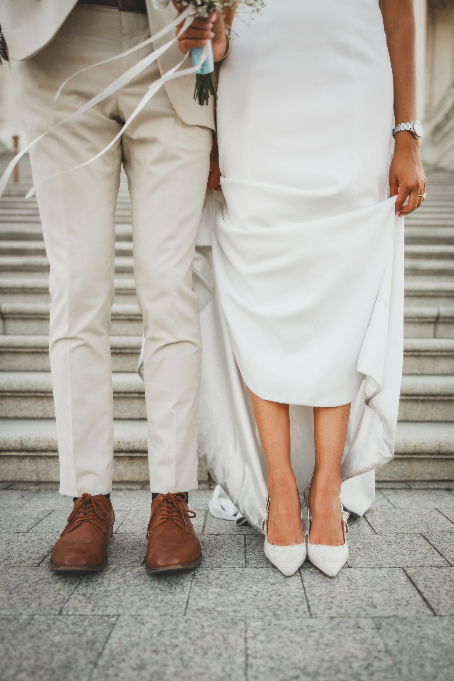 Wedding couple's feet on Capitol steps showing brown dress shoes and white heels.