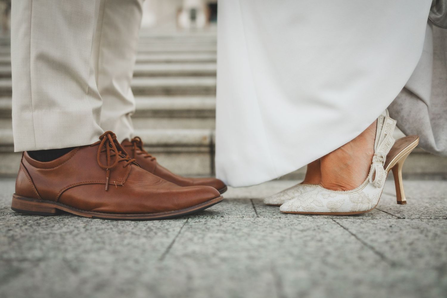 Close-up of bride and groom's shoes on marble steps.