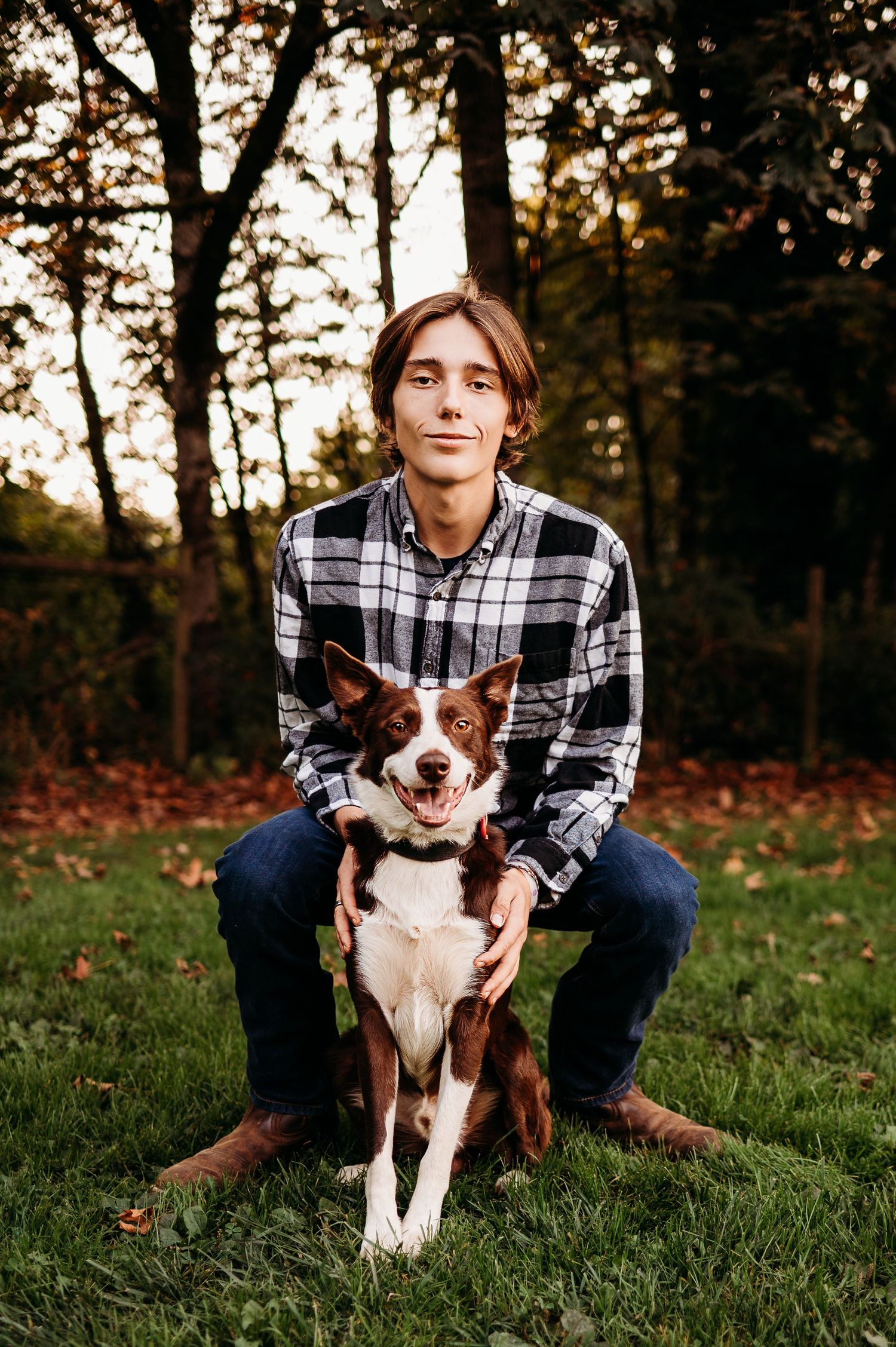 Person in plaid shirt sitting outdoors with brown and white border collie dog.