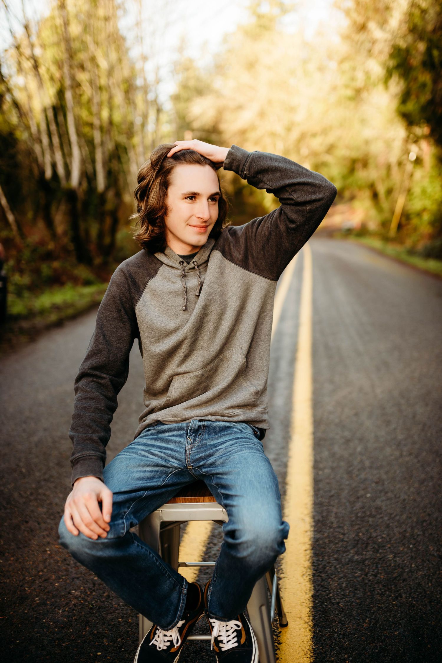 Person in casual attire sitting on pavement during golden hour photography session.