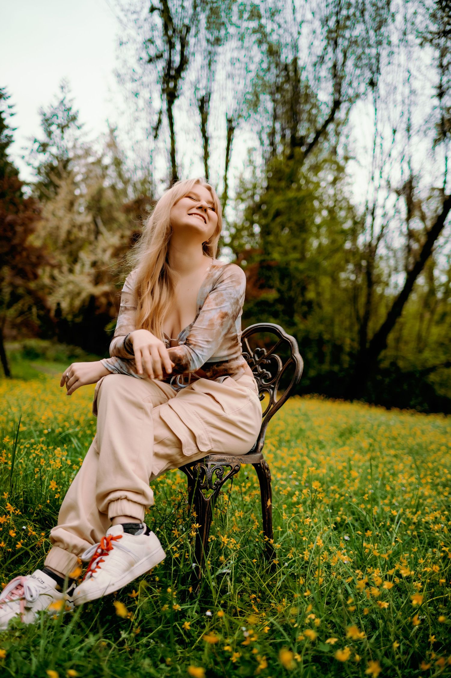 Someone laughs while sitting on a vintage bench in a spring meadow filled with yellow wildflowers.
