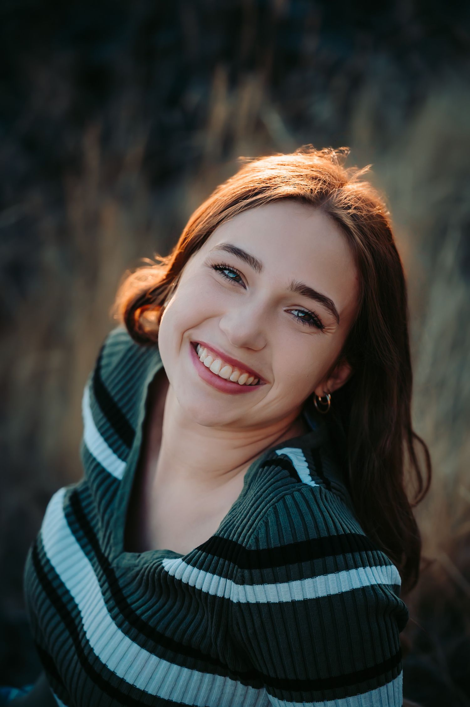 Close-up portrait showing warm smile and striped turtleneck sweater.