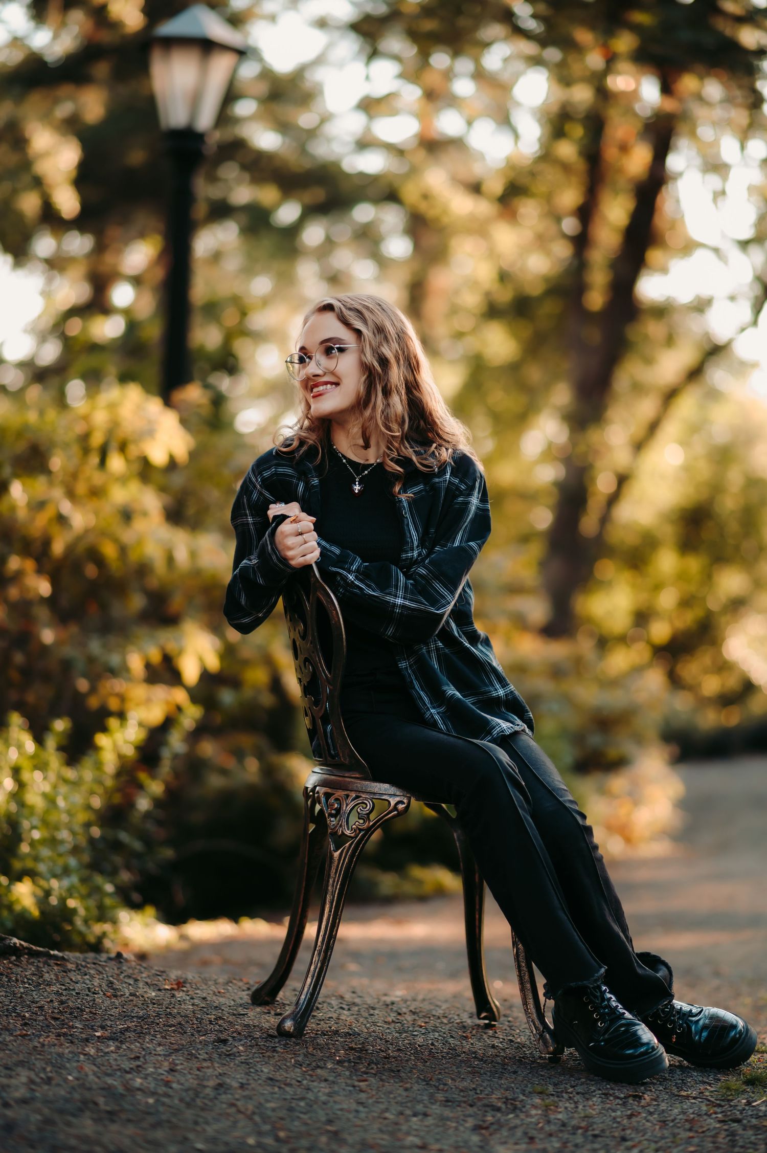 Person in black outfit lounging on vintage chair outdoors during golden hour.