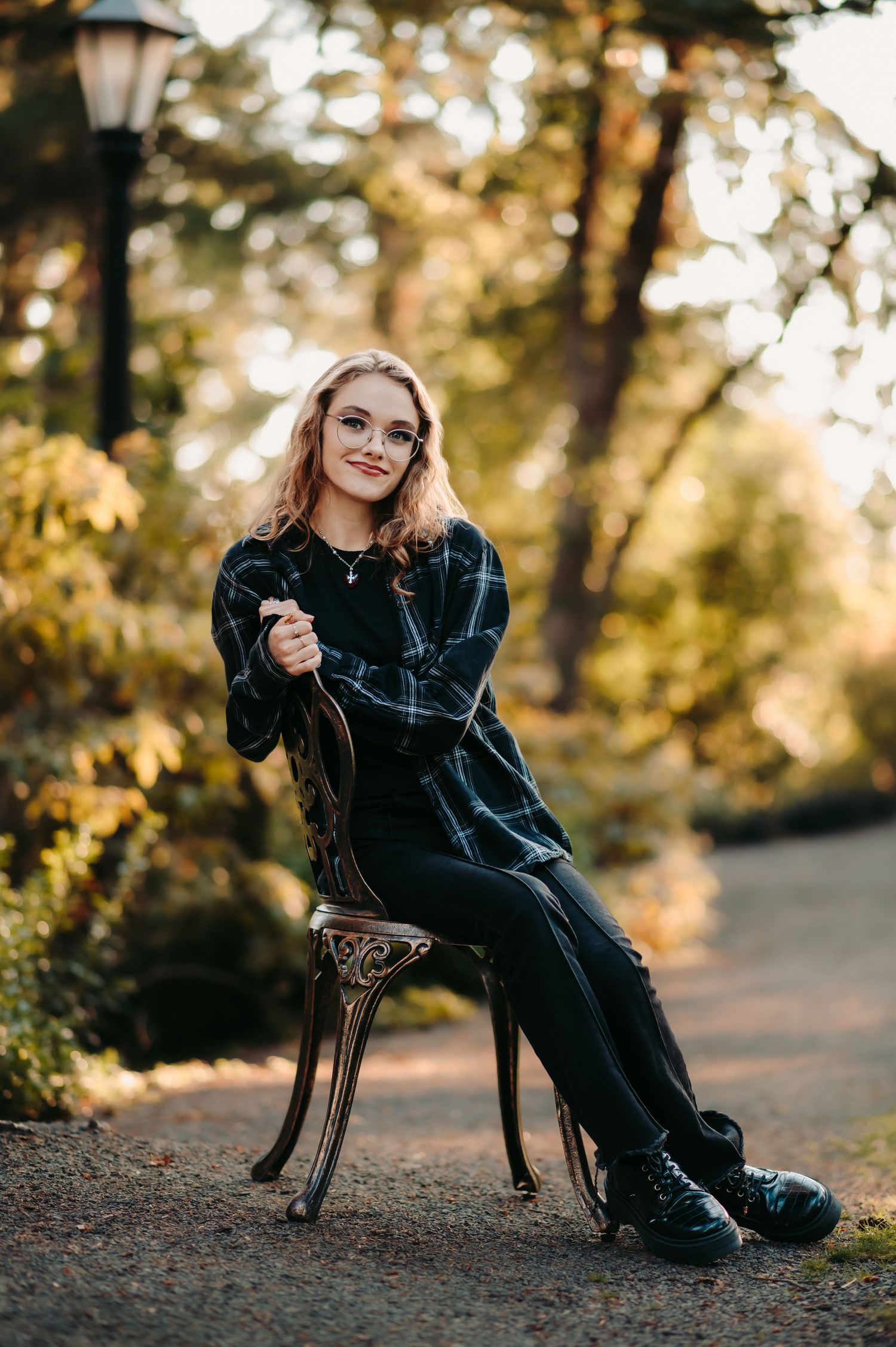 Person relaxing in dark outfit on antique chair in autumn forest setting.