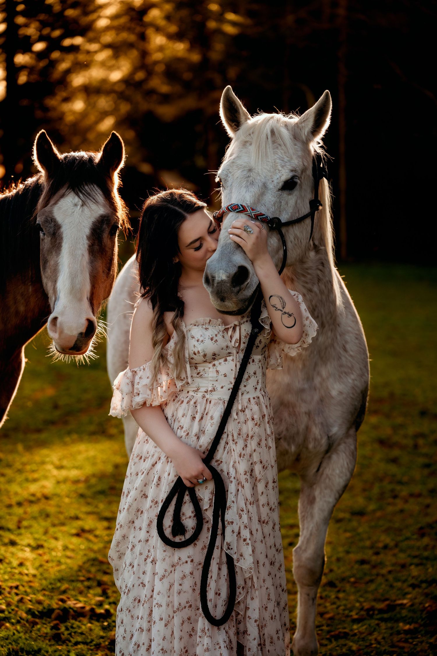 Person in floral dress embracing white speckled horse during sunset photoshoot.
