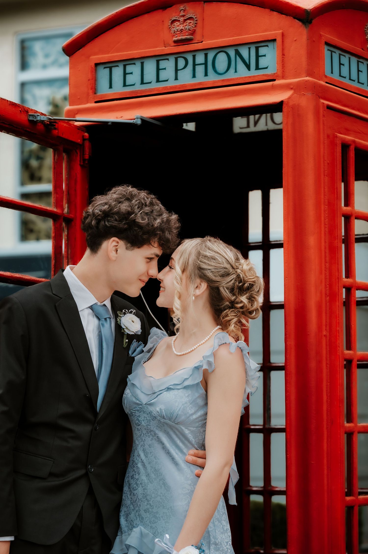 Couple poses romantically by classic red British telephone booths.