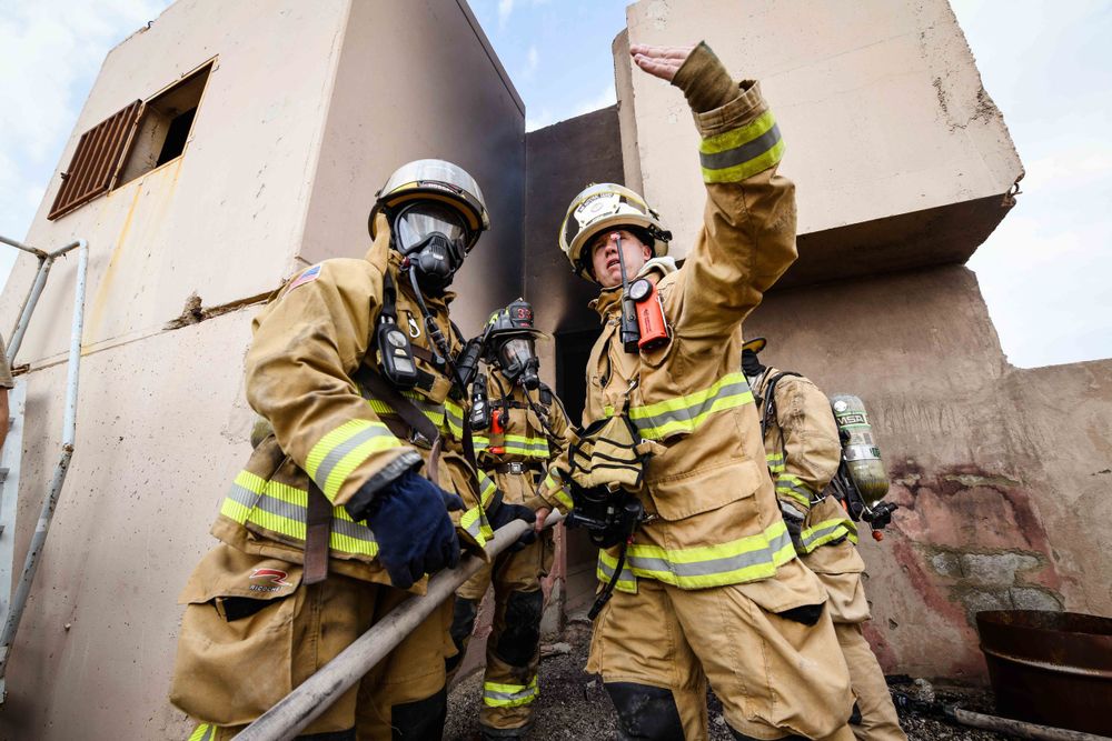 Firefighters in protective gear coordinating during an emergency response operation.