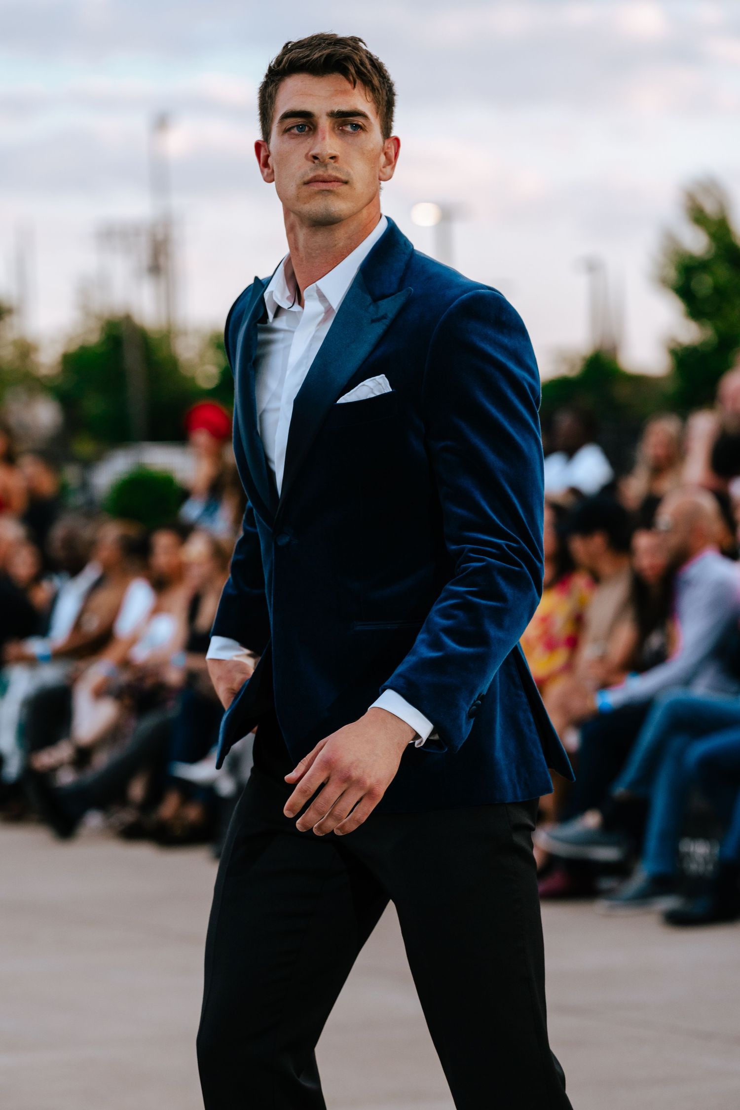 Male runway model striking a side pose as he stops in front of the photographers pit.