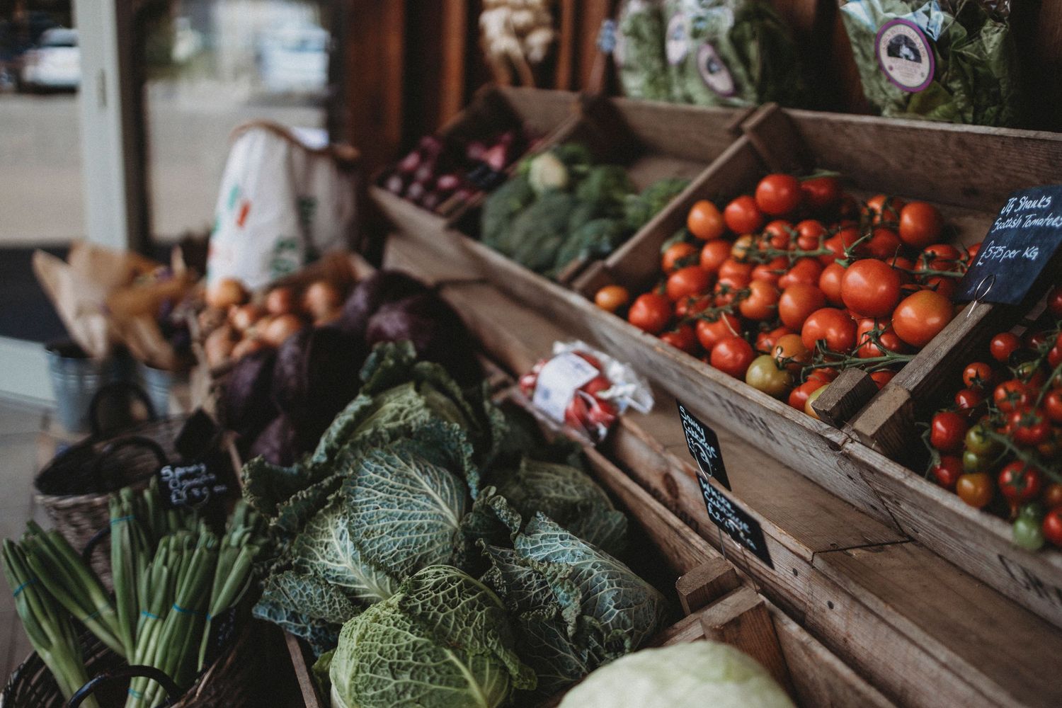 Fresh produce display with cabbage and tomatoes at a local market stand.