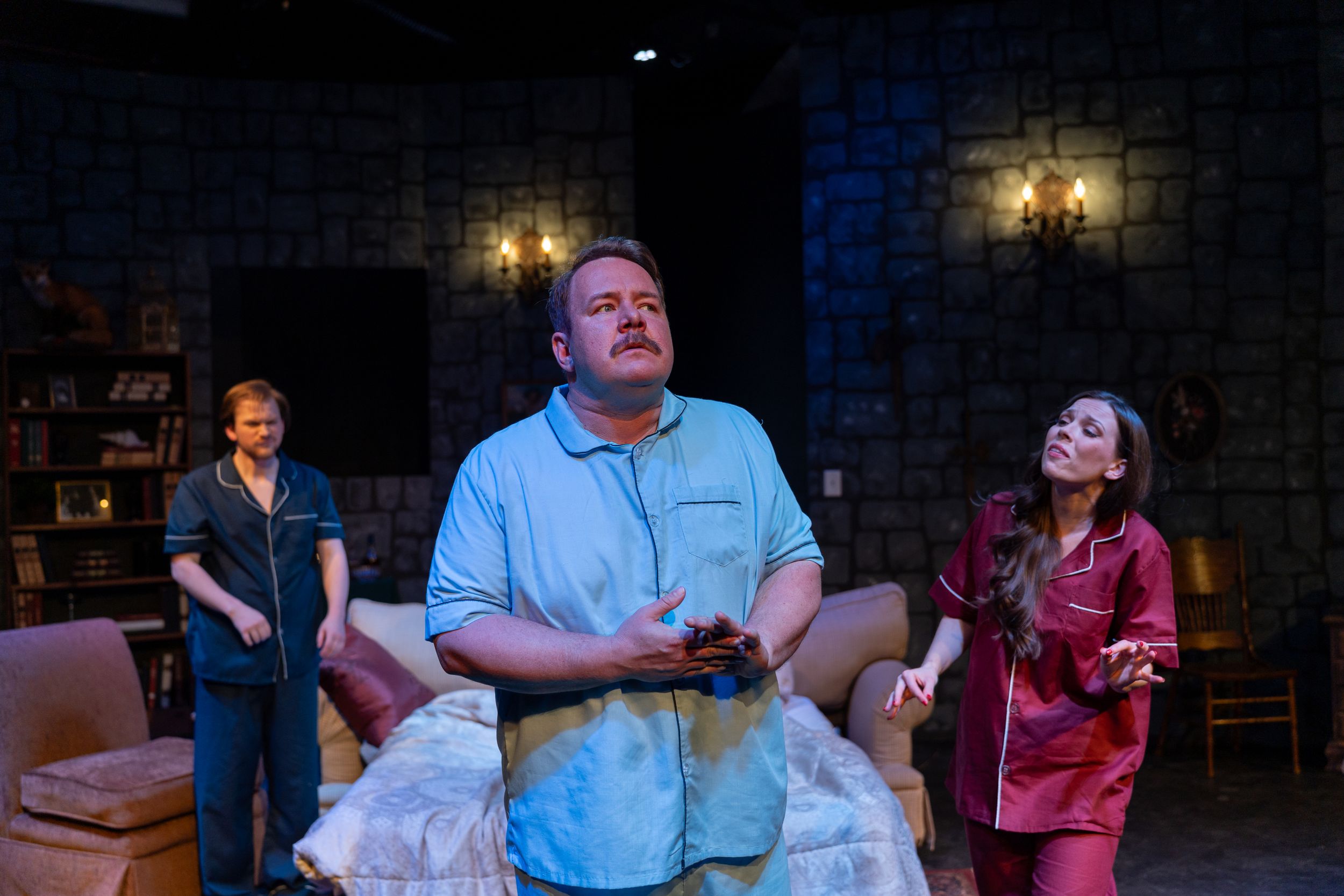 Theater performers act out an emotional scene on stage with dramatic lighting.