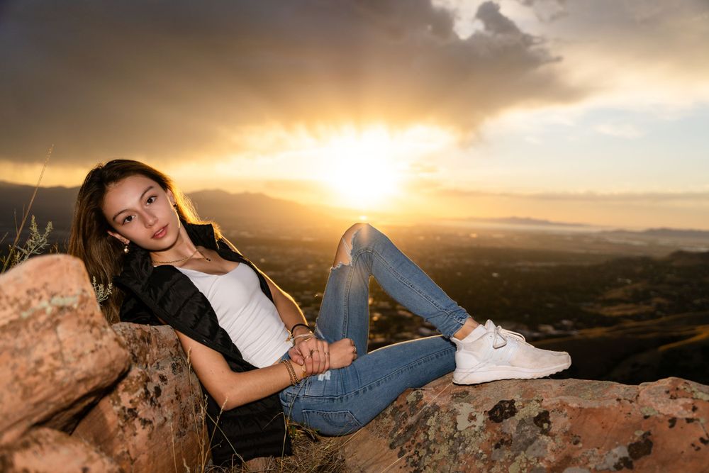 Relaxed sunset portrait on mountain rock with golden light and valley views.