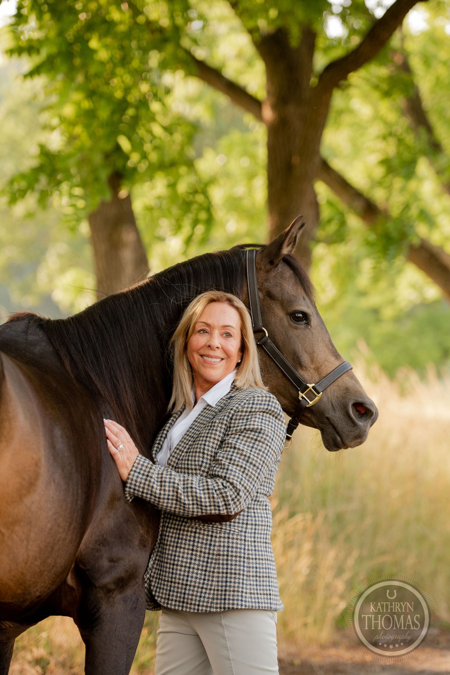 Dark horse and handler in plaid blazer pose together against autumn foliage.