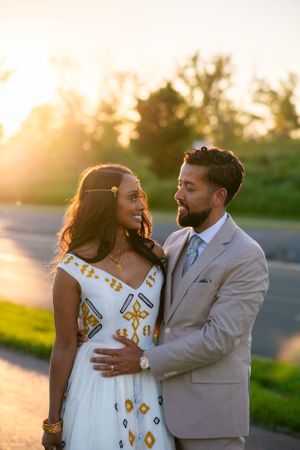 Golden hour wedding photo, bride and groom facing each other with trees in the background. Bride is in traditional Zuria.