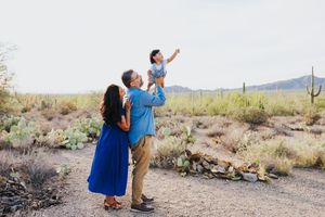 Family enjoying playful moments together among desert flora and mountains.