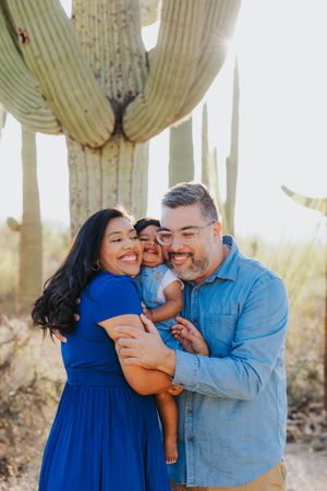 A loving family shares joyful moments together among towering saguaro cacti in the Arizona desert.