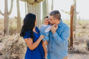 Family embraces and laughs together during a desert photoshoot with saguaro cacti in the background.