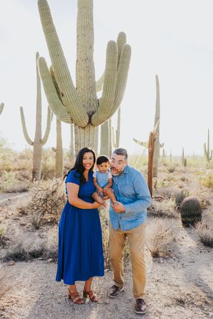 A family plays and poses playfully in a desert landscape filled with majestic saguaro cacti.