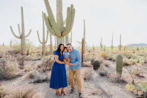Family photo session in a scenic desert setting with giant saguaro cacti as backdrop.