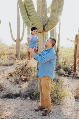 Playful moment captured in a desert landscape with towering saguaro cacti in the background.