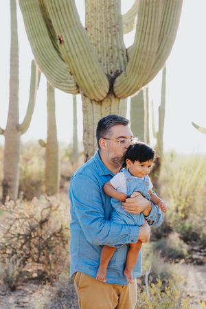 Sweet family moment shared between parent and child among majestic saguaro cacti in the desert.