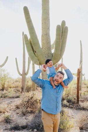 Energetic poses and smiles photographed in a scenic desert setting with giant cacti.