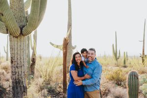Loving family embraces photographed against a backdrop of majestic desert cacti.