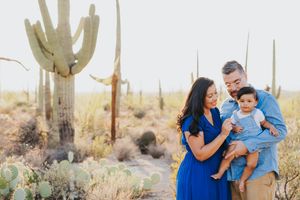 A family shares a joyful moment together among saguaro cacti in the Arizona desert.