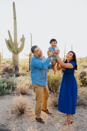 A playful couple dances and laughs together in a desert setting with saguaro cacti.